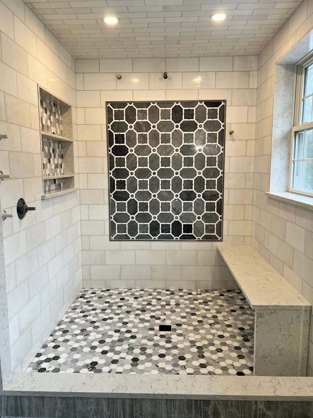 A bathroom with a walk in shower and a bench.