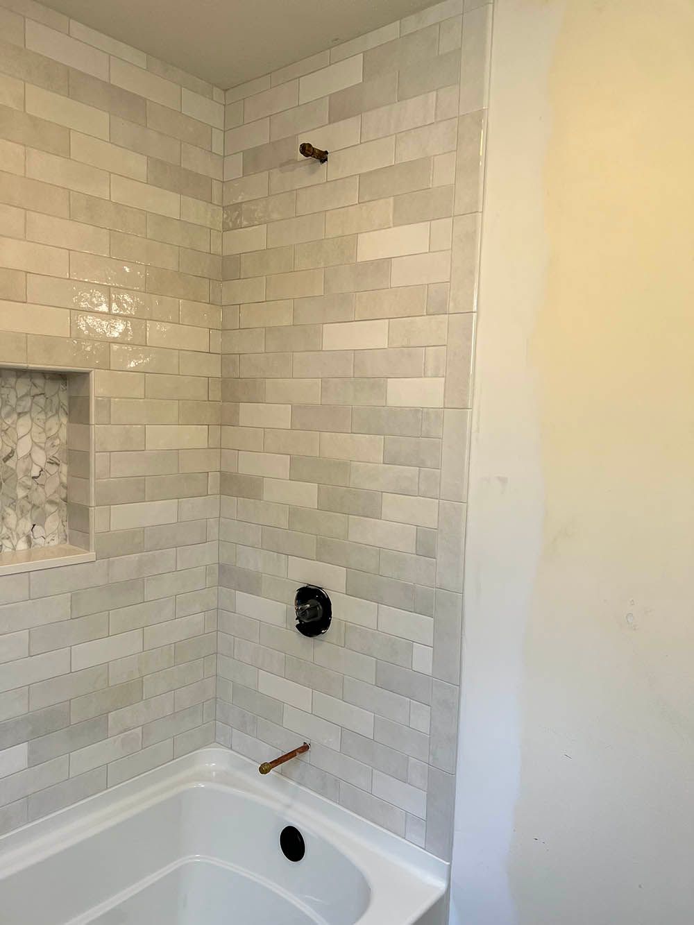A bathroom with white tiles and a bathtub.