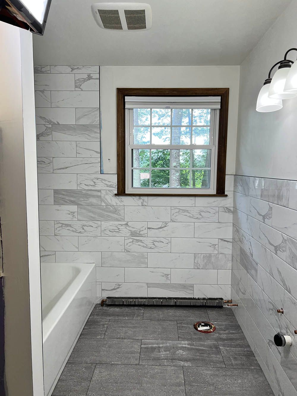A bathroom with white tiles and a window.