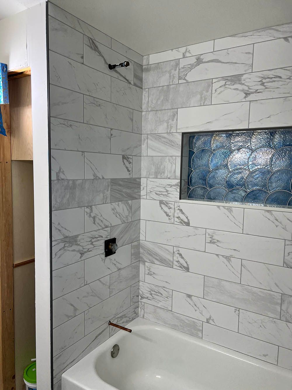 A bathroom with marble tiles and a bathtub.