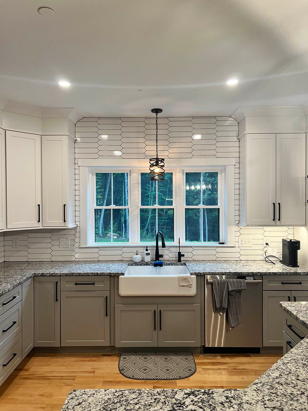 A kitchen with white cabinets , granite counter tops , stainless steel appliances , a sink and a window.