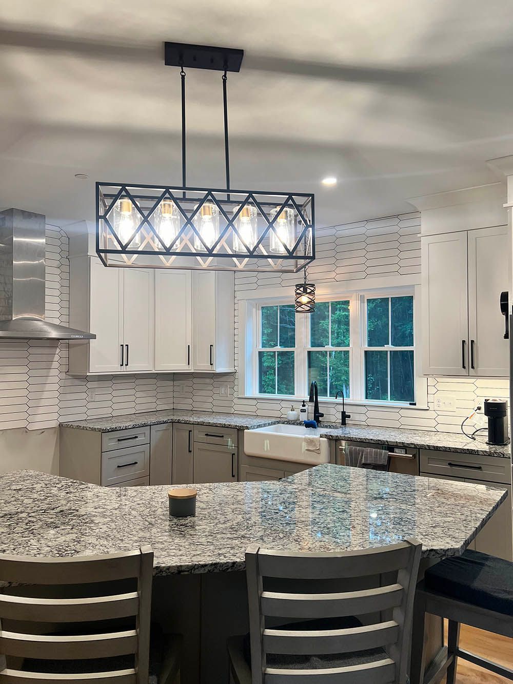 A kitchen with a large island and a chandelier hanging from the ceiling.