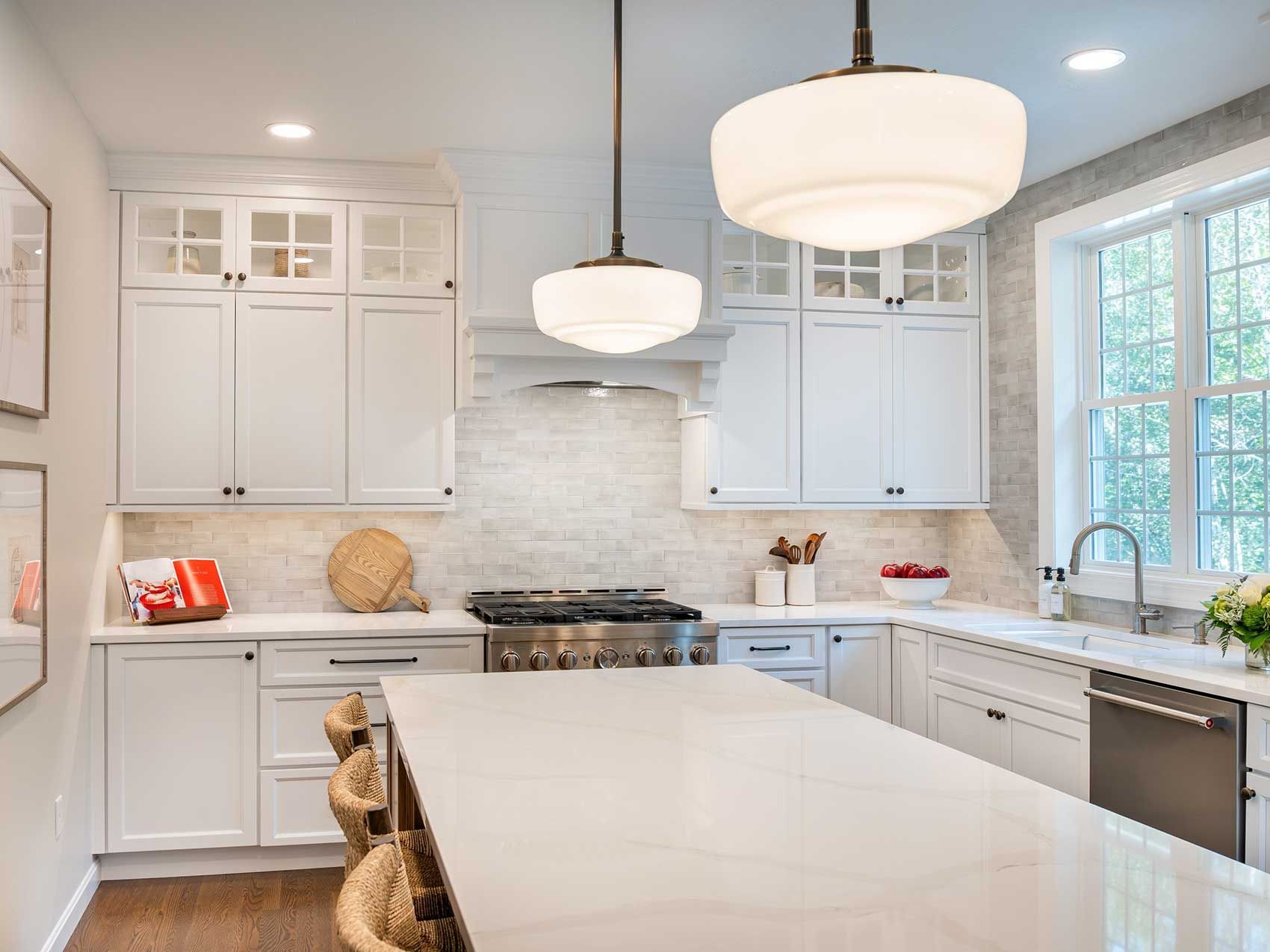 A kitchen with white cabinets , a stove , a sink , and a large island.