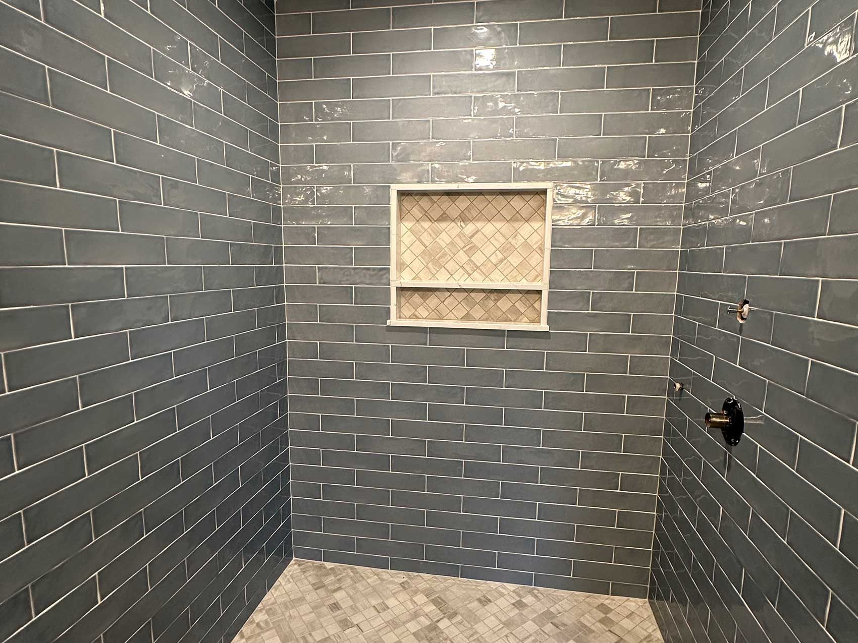 A bathroom with a shower stall and a shelf in the wall.