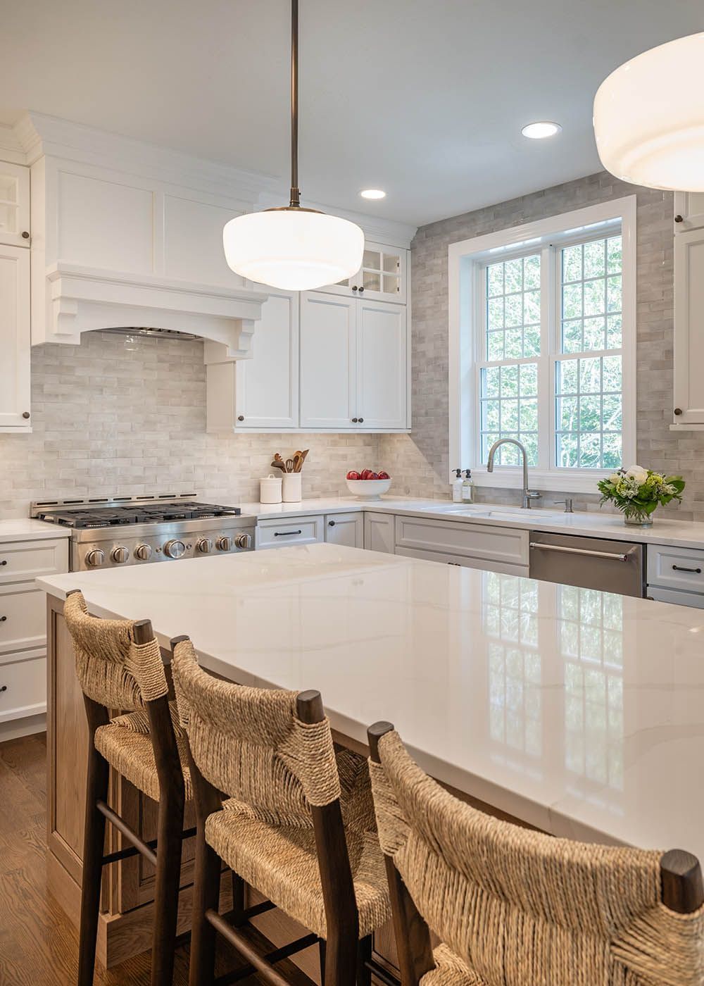 A kitchen with white cabinets and a large island with wicker chairs.