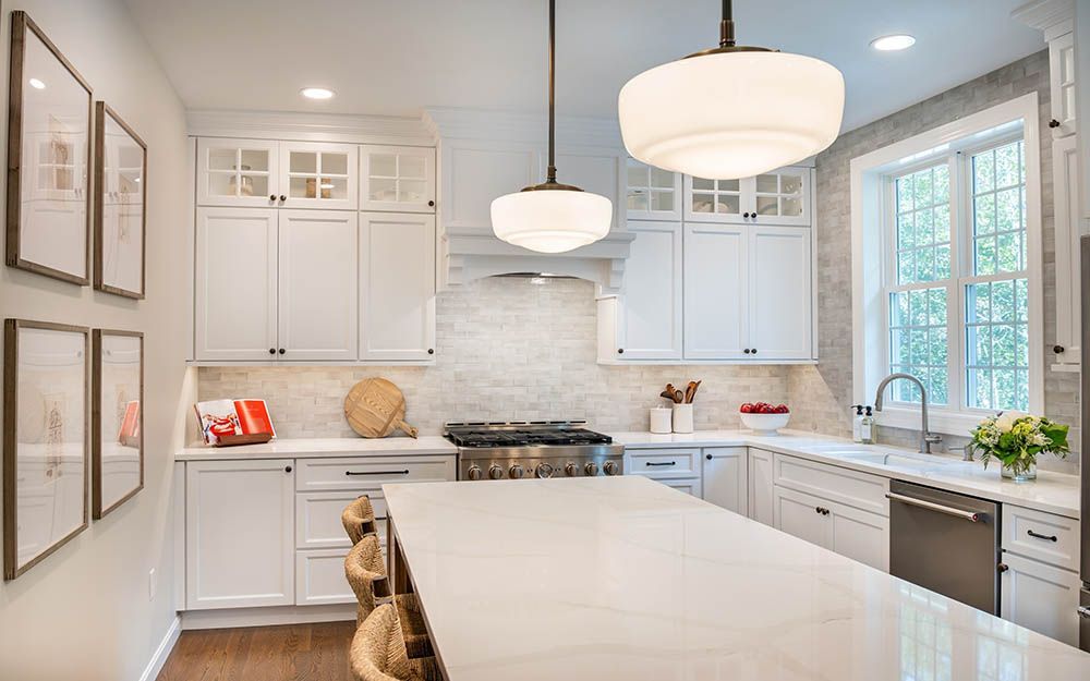 A kitchen with white cabinets , stainless steel appliances , and a large island.