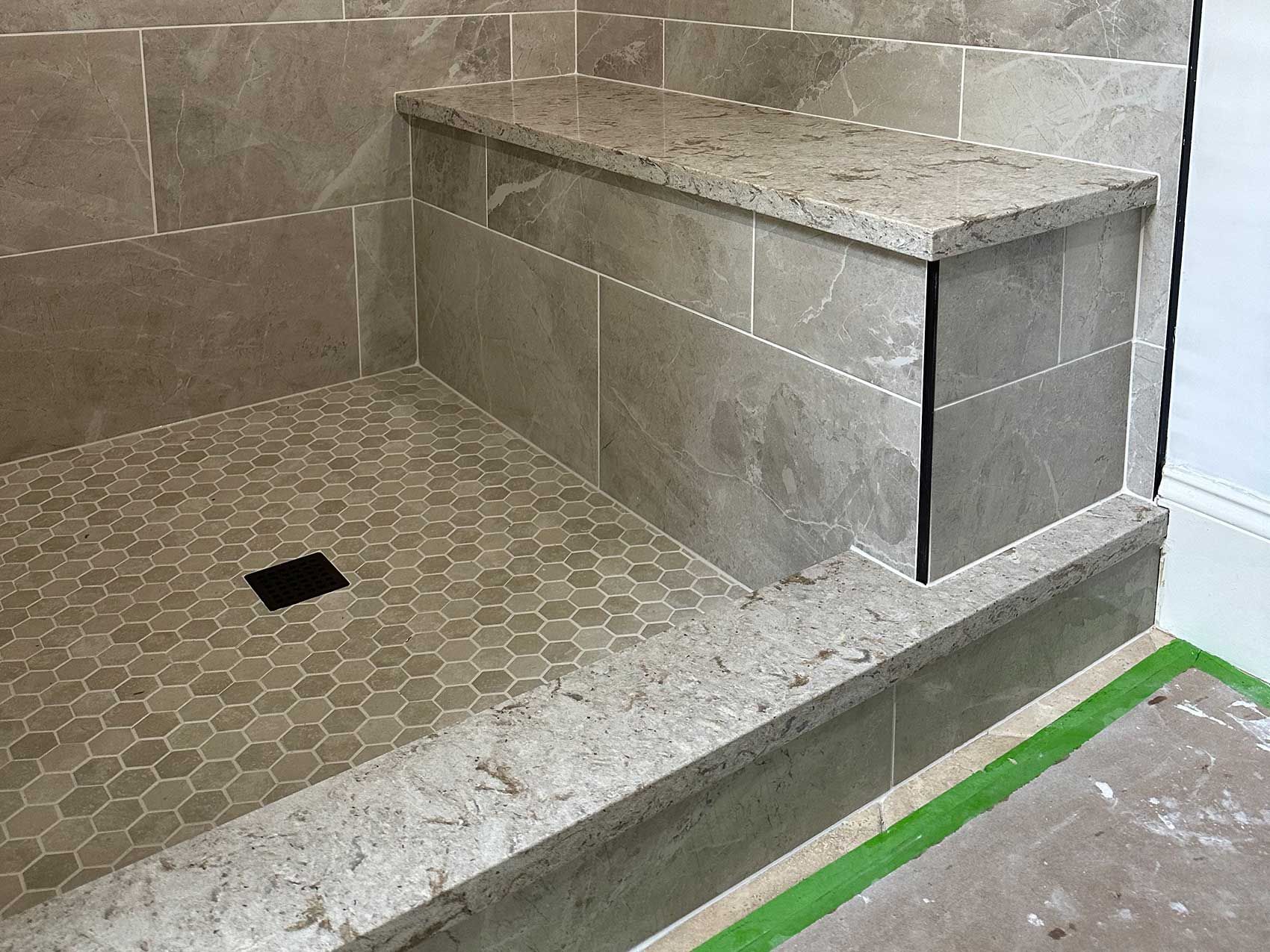 A shower stall with a bench and steps in a bathroom.