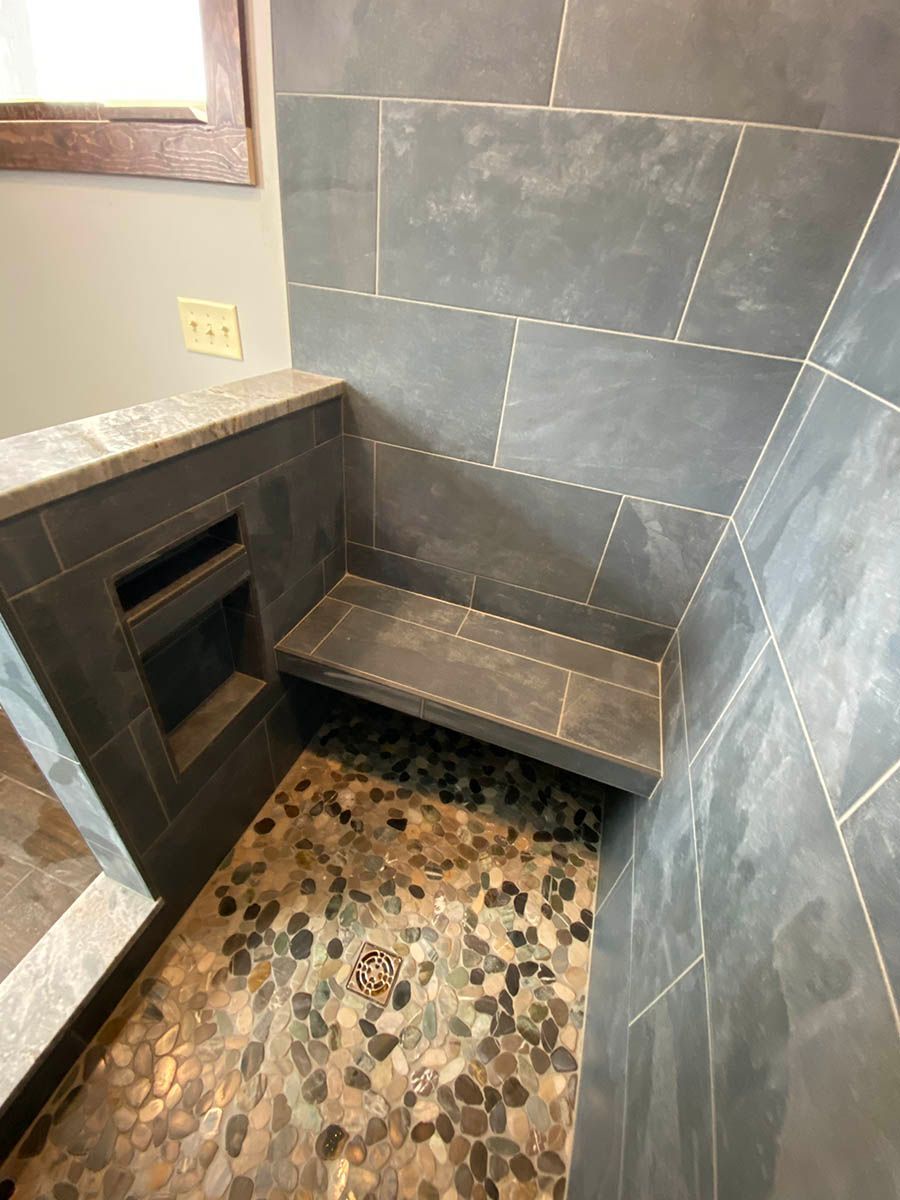 A shower with a bench in it and a tiled floor.