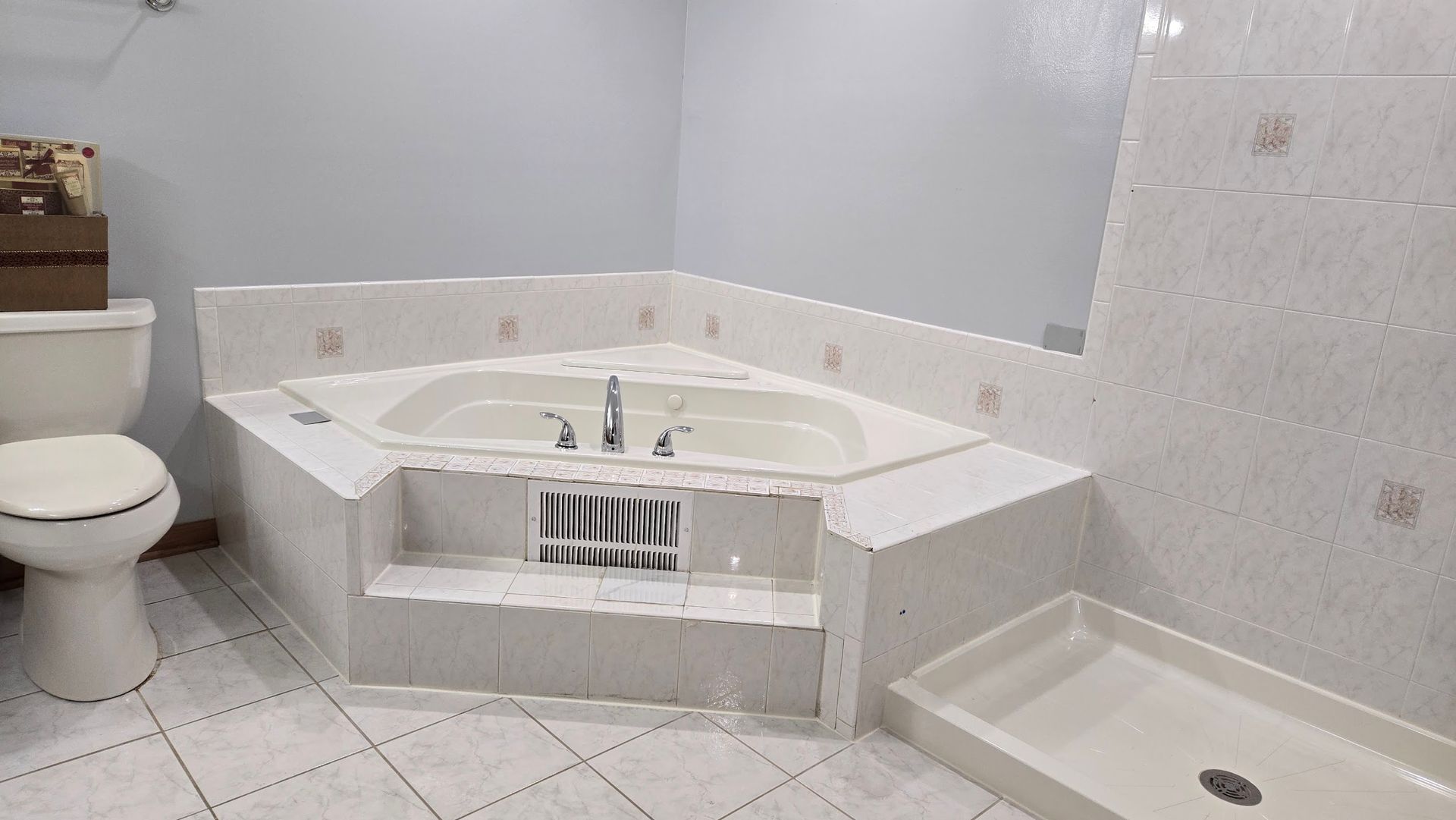 Bathroom with corner jetted tub, toilet, and shower stall on white tile floor