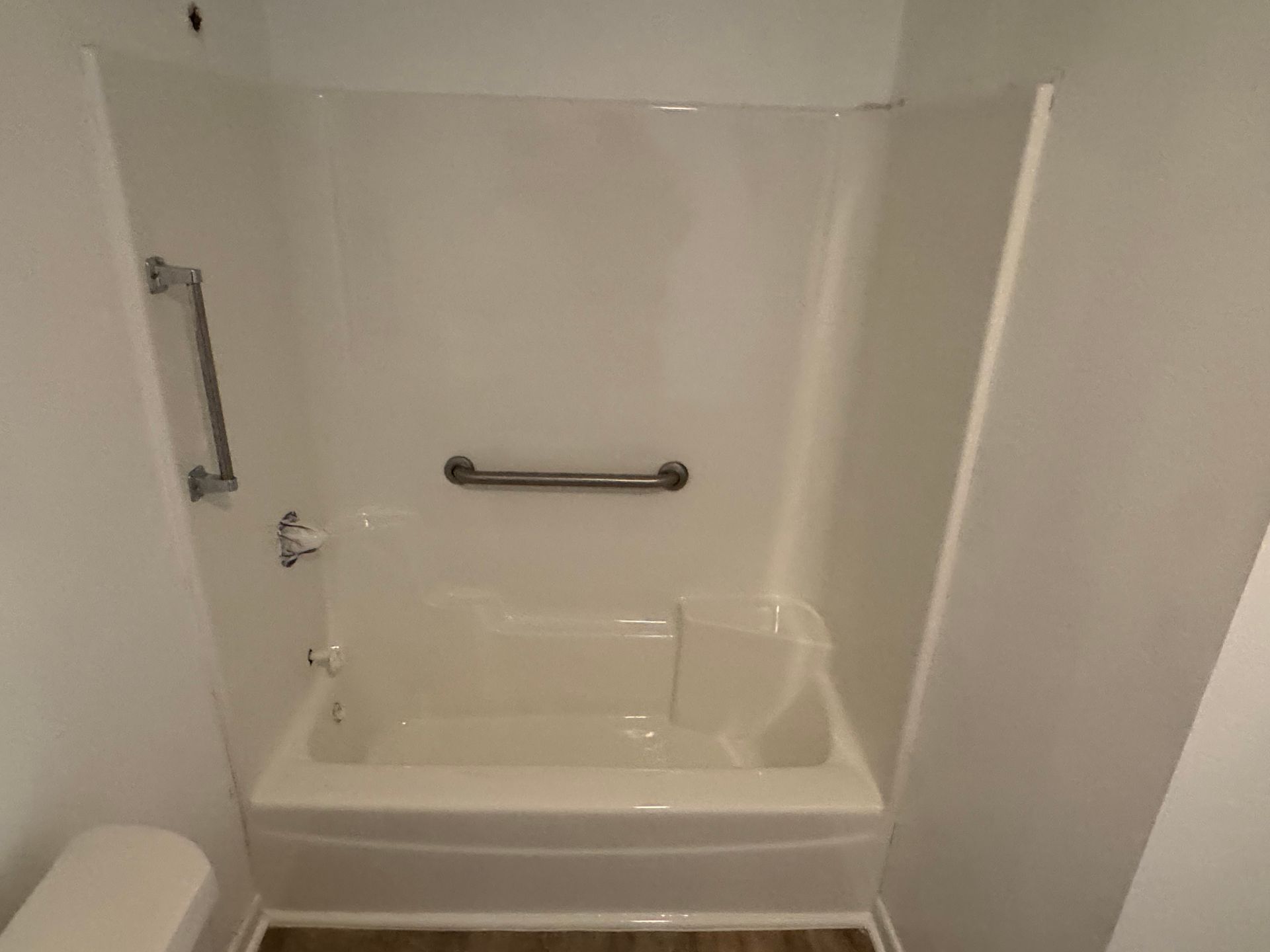 A white bathtub in a bathroom with a shower stall.