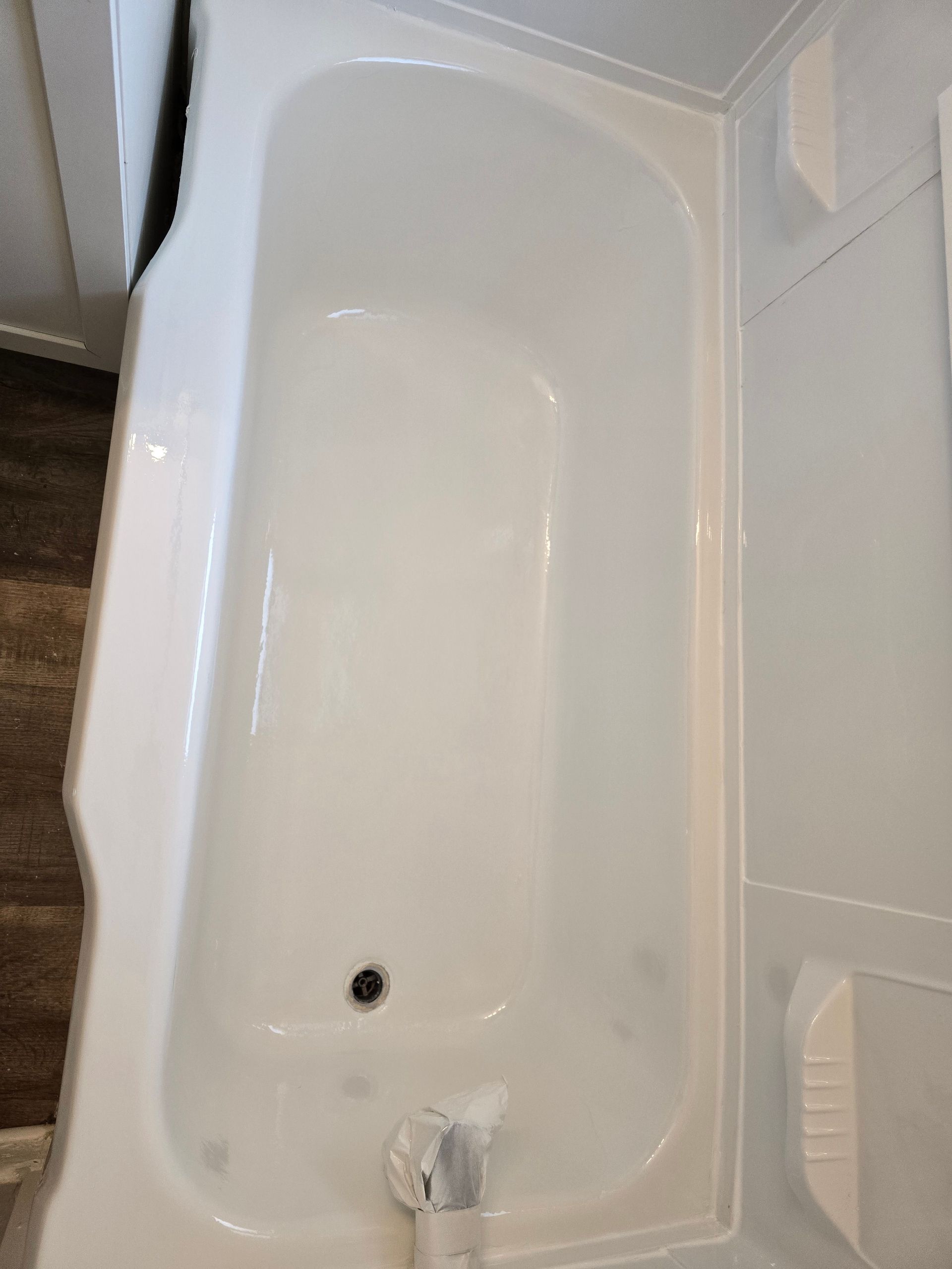 A white bathtub is sitting on top of a wooden floor in a bathroom.