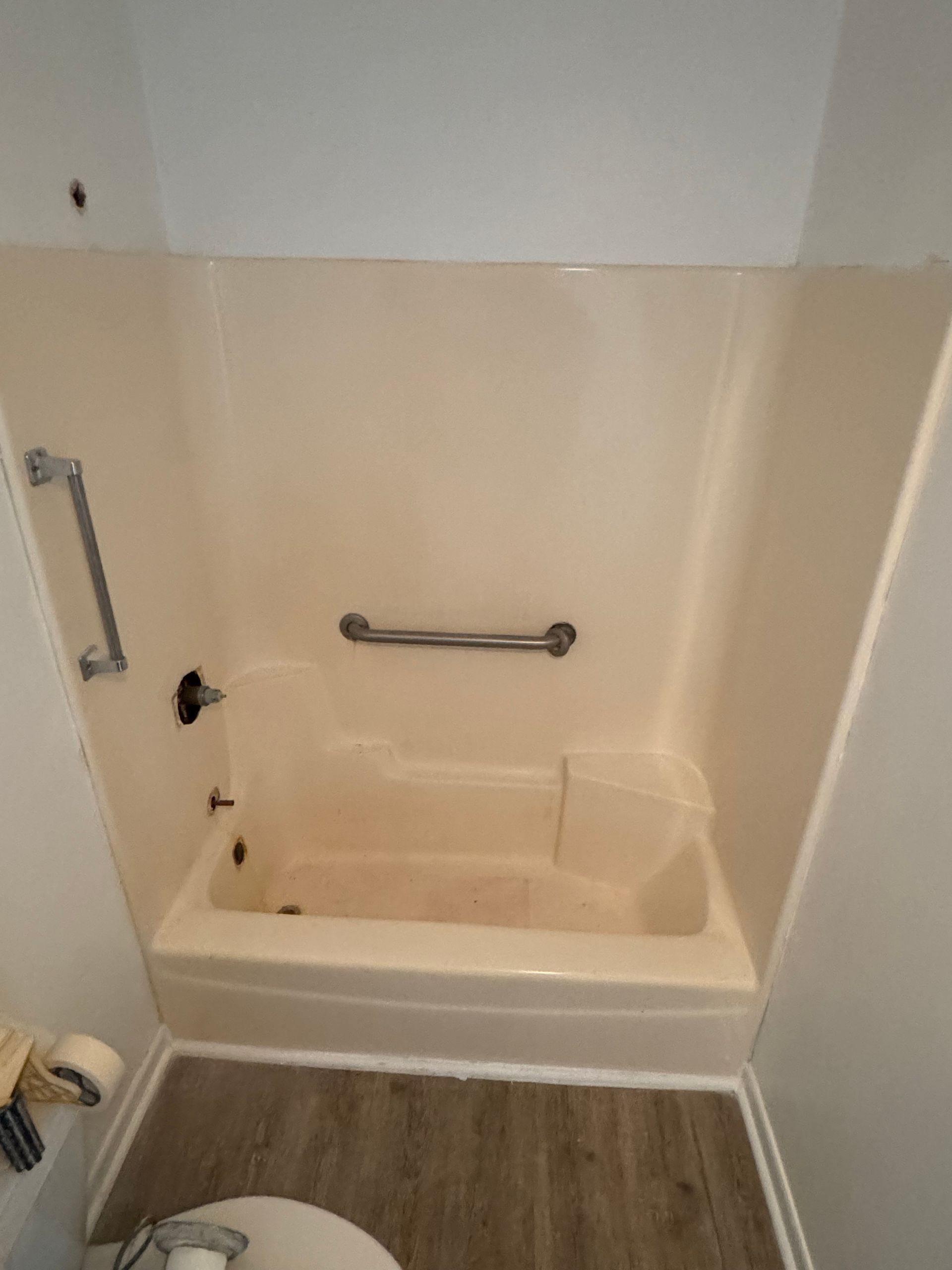 A dirty bathtub in a bathroom next to a shower.