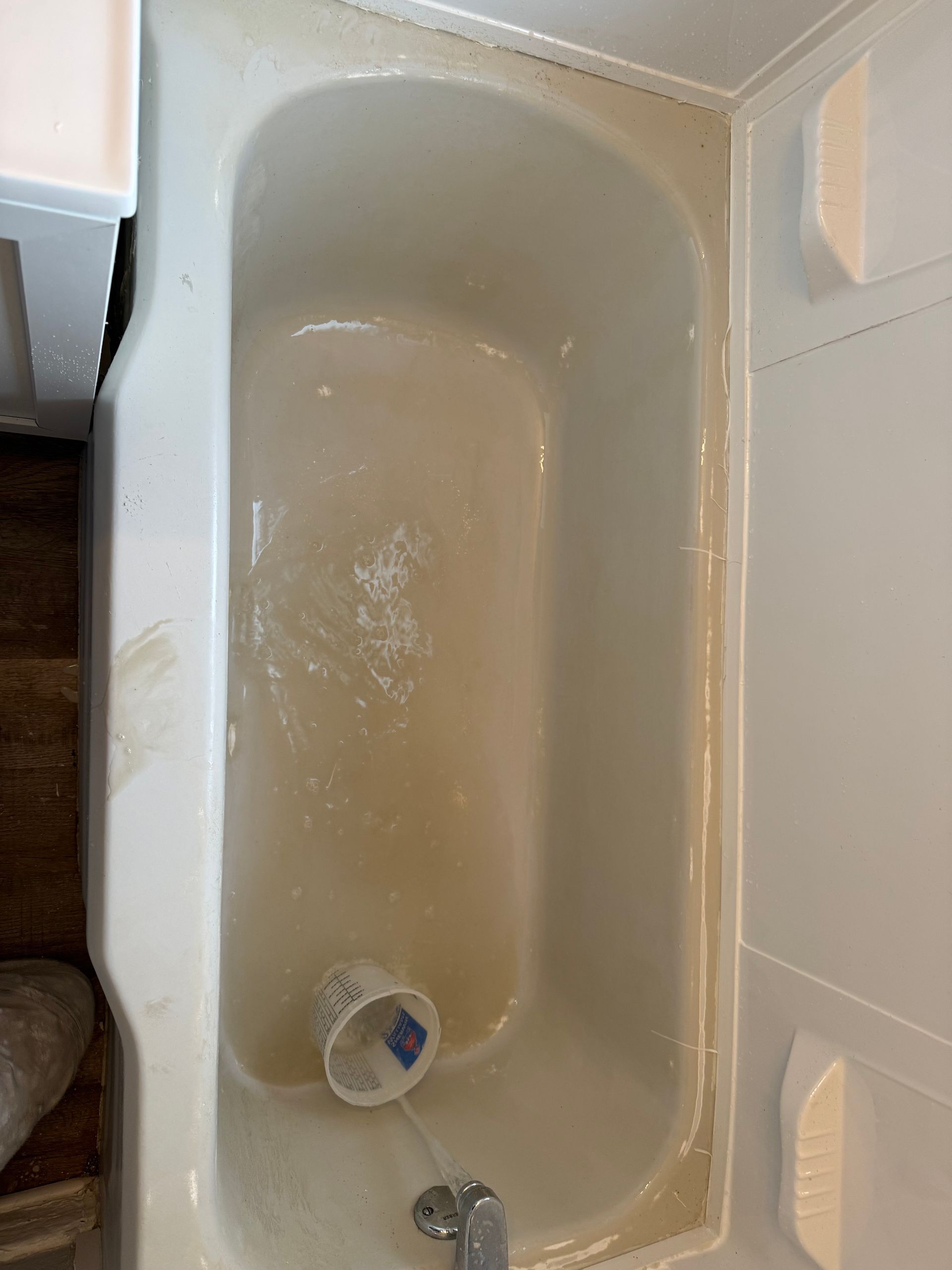 A bathtub with peeling paint on the floor in a bathroom.