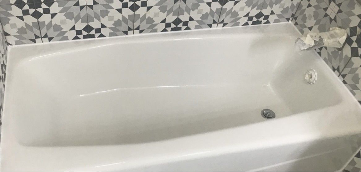 A white bathtub is sitting in a bathroom next to a tiled wall.