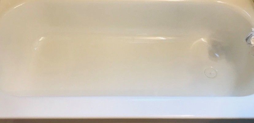 A white bathtub is sitting on top of a wooden floor in a bathroom.
