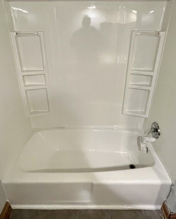 A white bathtub in a bathroom with a shower stall.