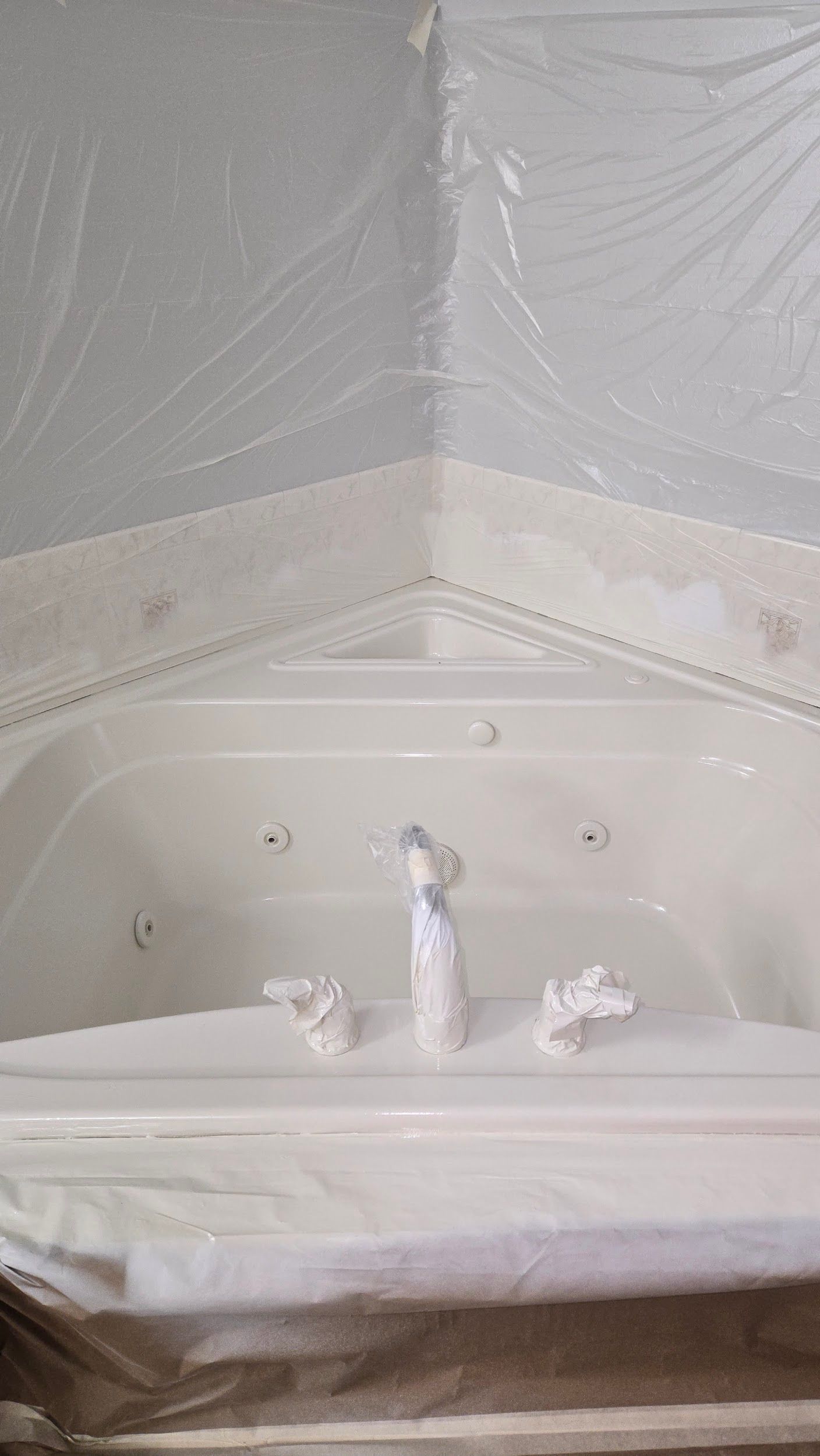 A white bathtub is covered in plastic wrap in a bathroom.