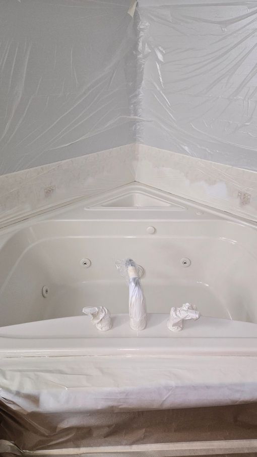 A white bathtub is covered in plastic wrap in a bathroom.