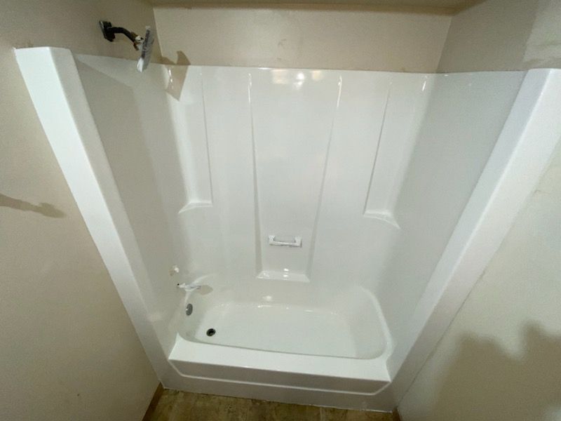 There is a bathtub in the shower with a shower head.