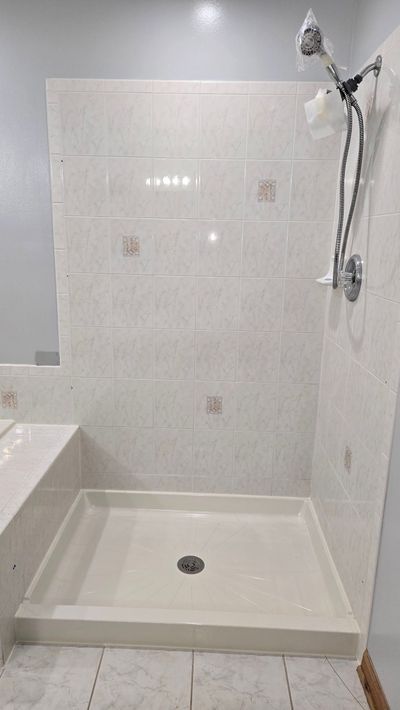 A bathroom with a shower stall and a shower head.