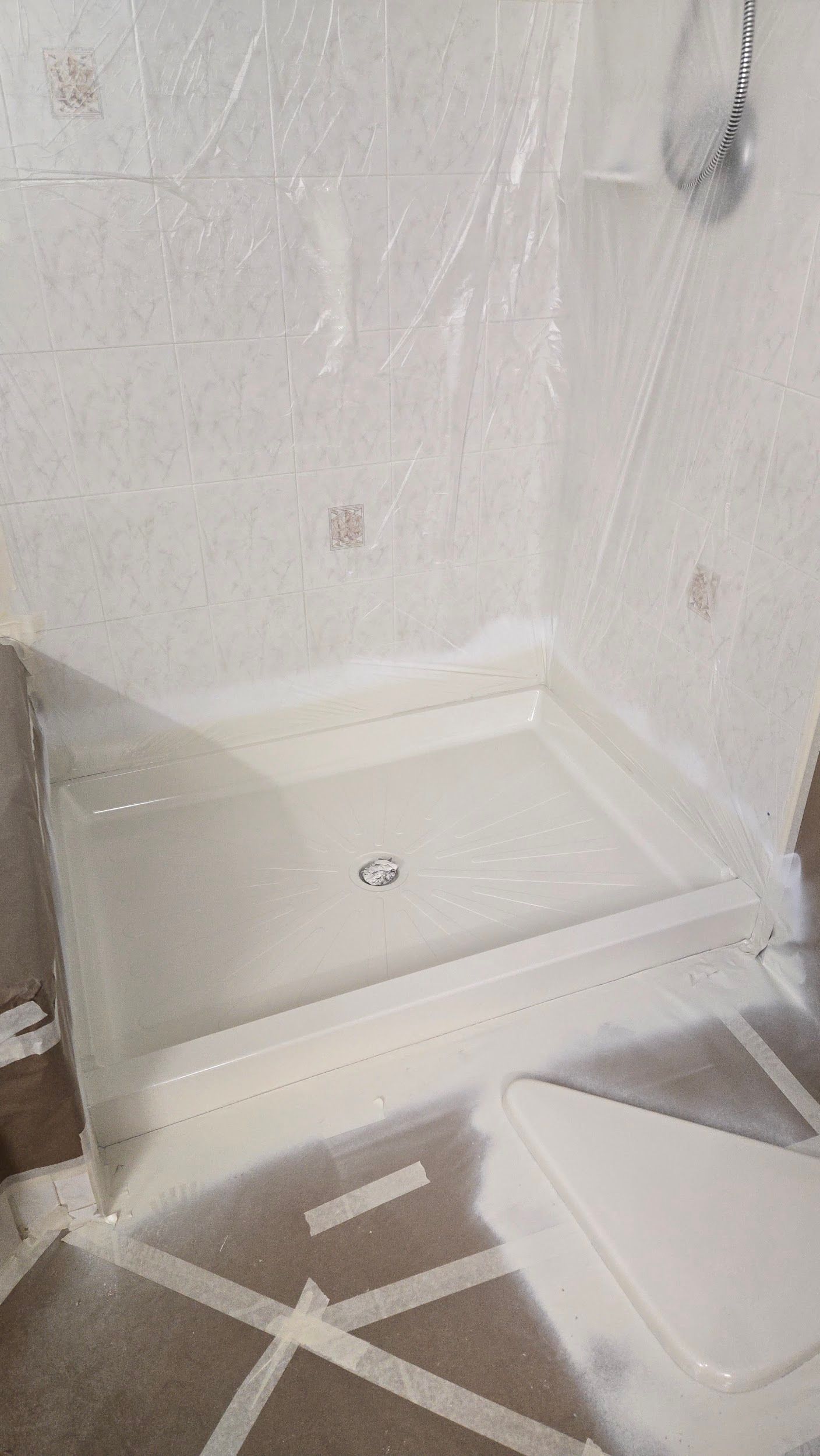 A shower stall is being painted in a bathroom.