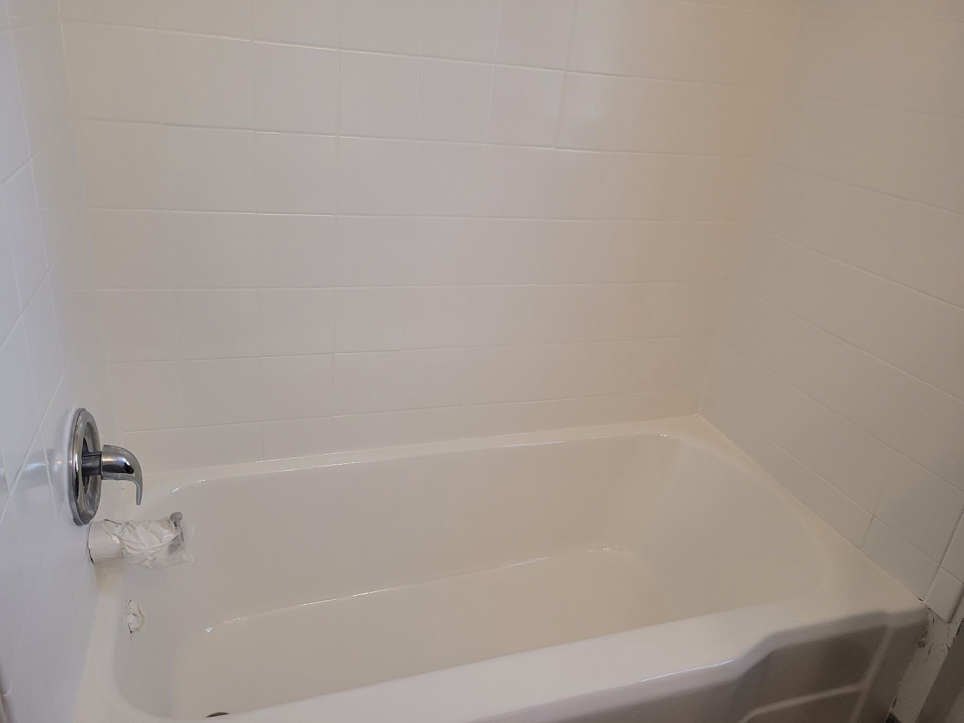 There is a bathtub in the bathroom with white tiles.