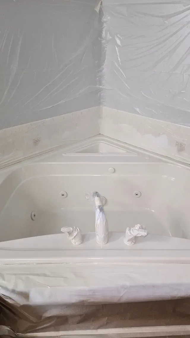 A white bathtub is covered in plastic wrap in a bathroom.