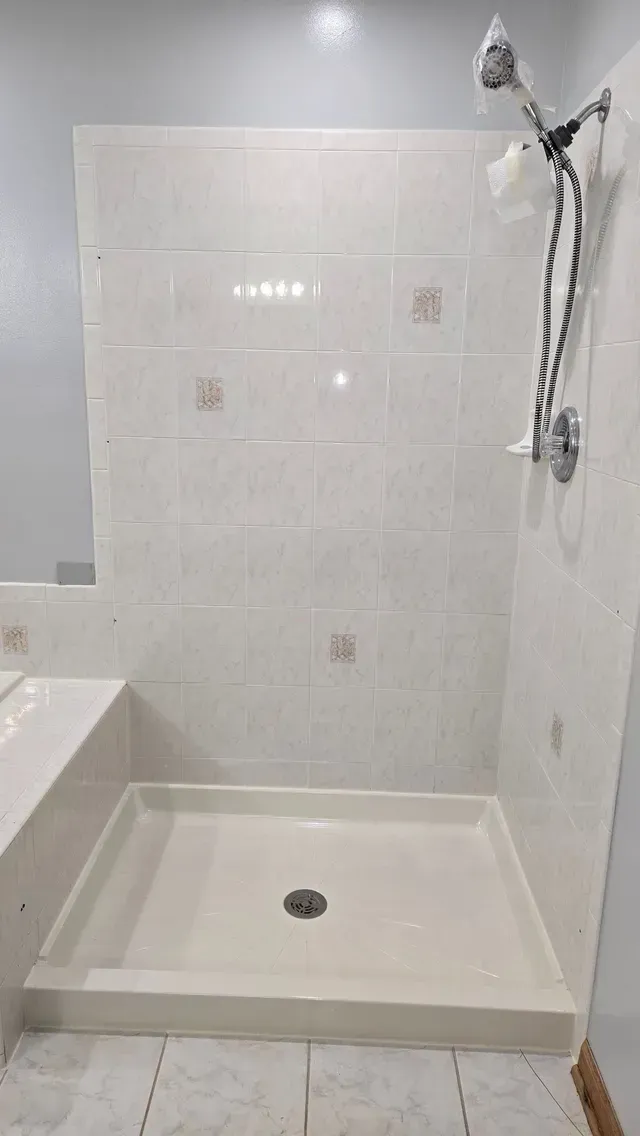 A bathroom with a shower stall and a shower head.