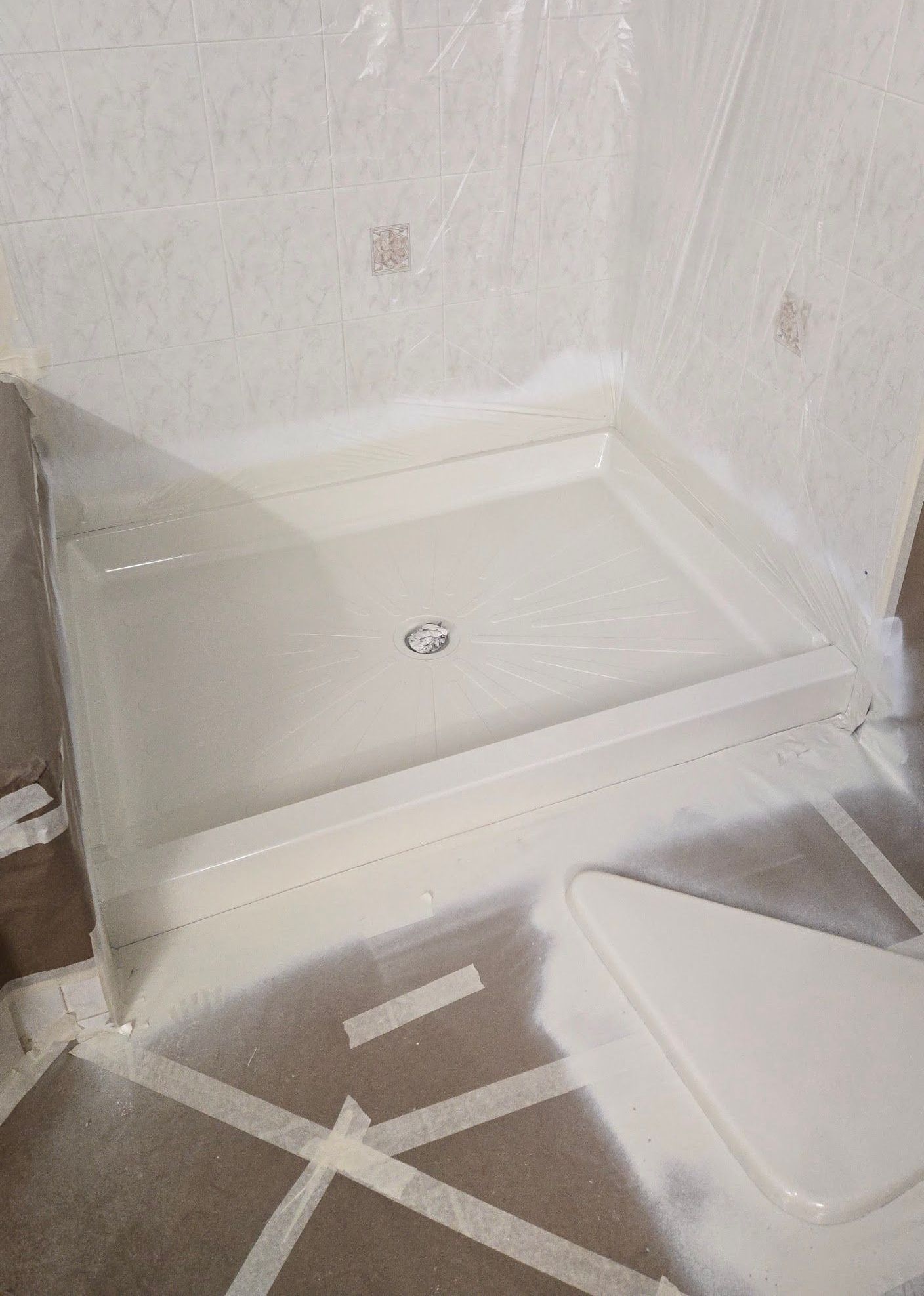 A shower stall is being painted white in a bathroom.