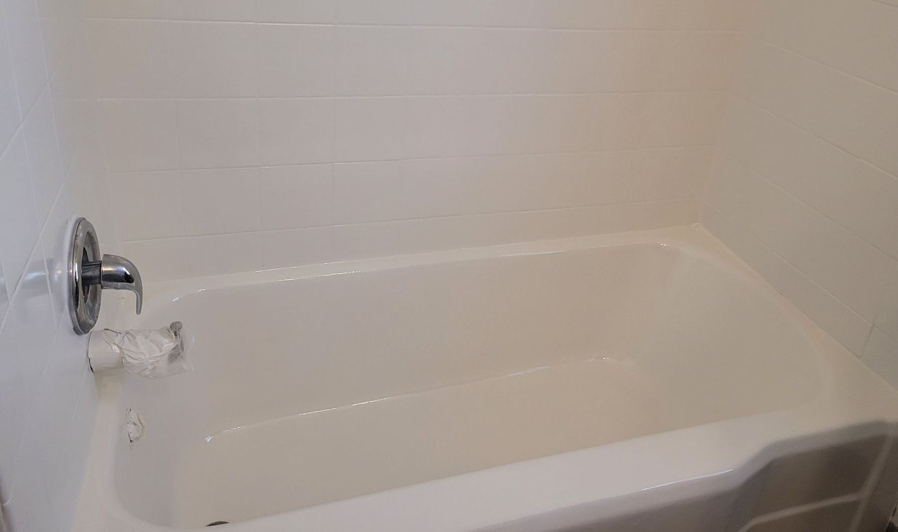 A white bathtub with a chrome shower head in a bathroom.