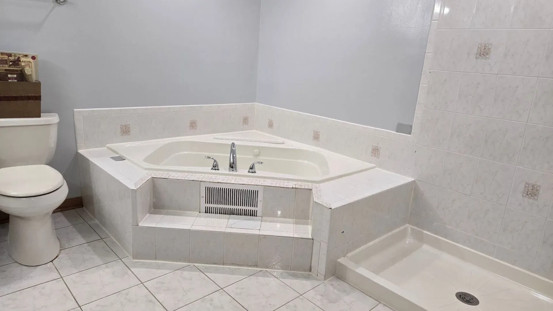 A bathroom with a jacuzzi tub , toilet and shower.