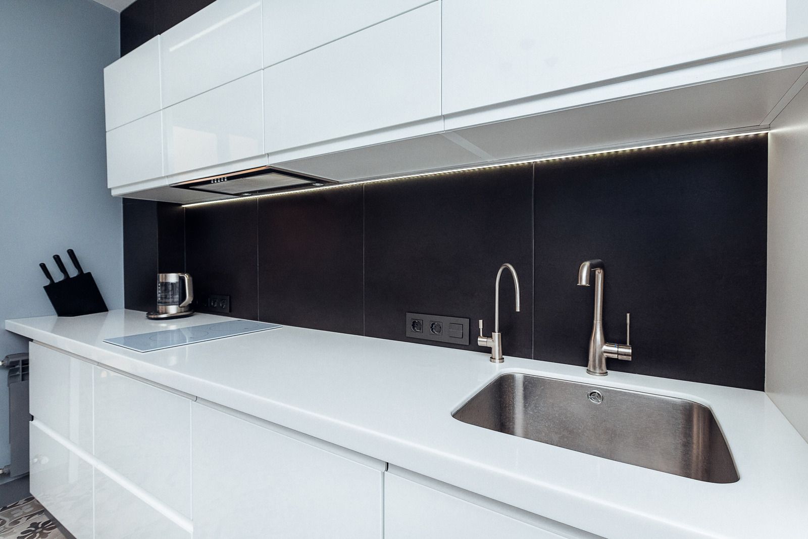 A kitchen with white cabinets and a stainless steel sink.