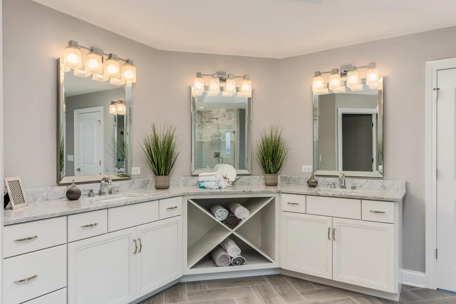 A bathroom with two sinks , two mirrors and a wine rack.