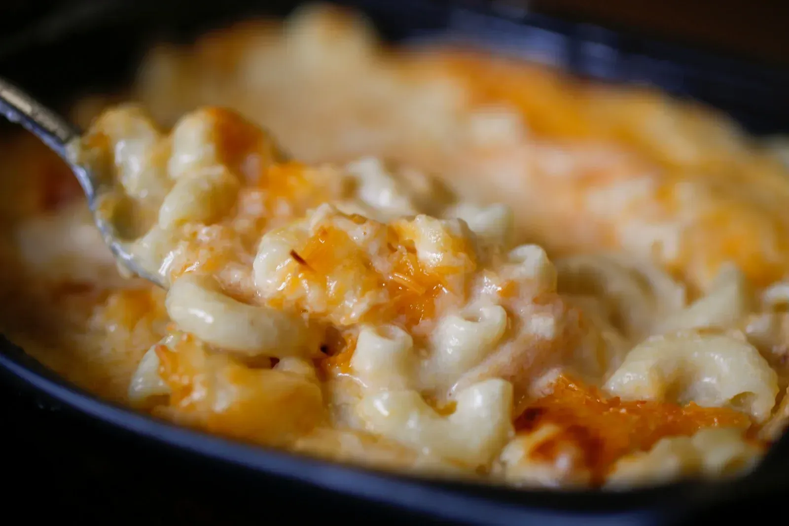 A bowl of macaroni and cheese with a spoon in it.