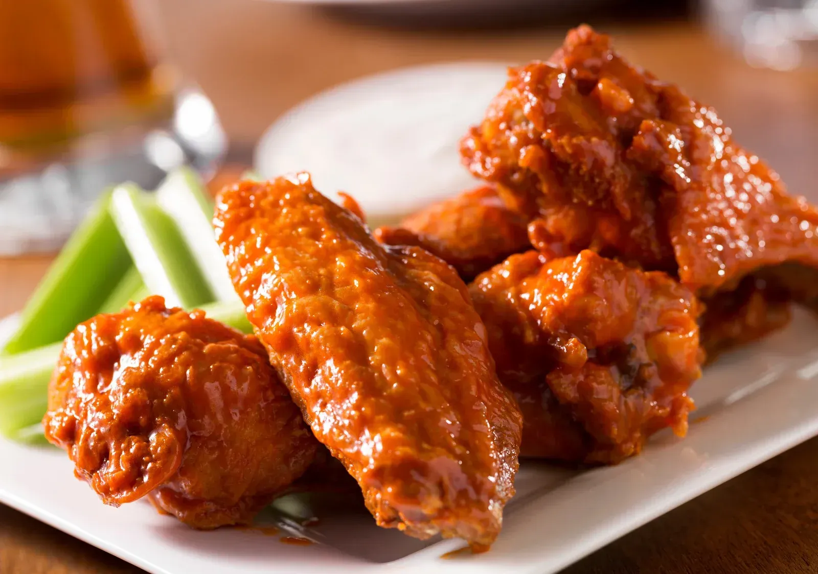 A white plate topped with chicken wings and celery sticks.