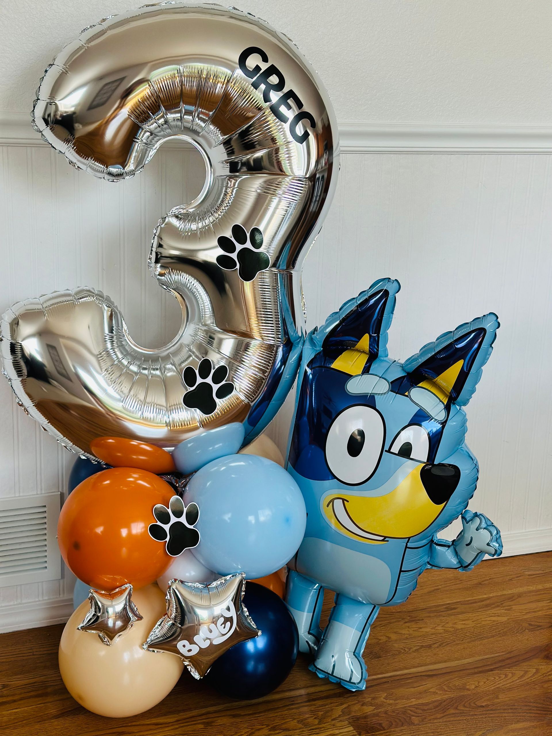 Balloon display for a 3rd birthday with a large silver number 3, Bluey character, and colorful balloons.