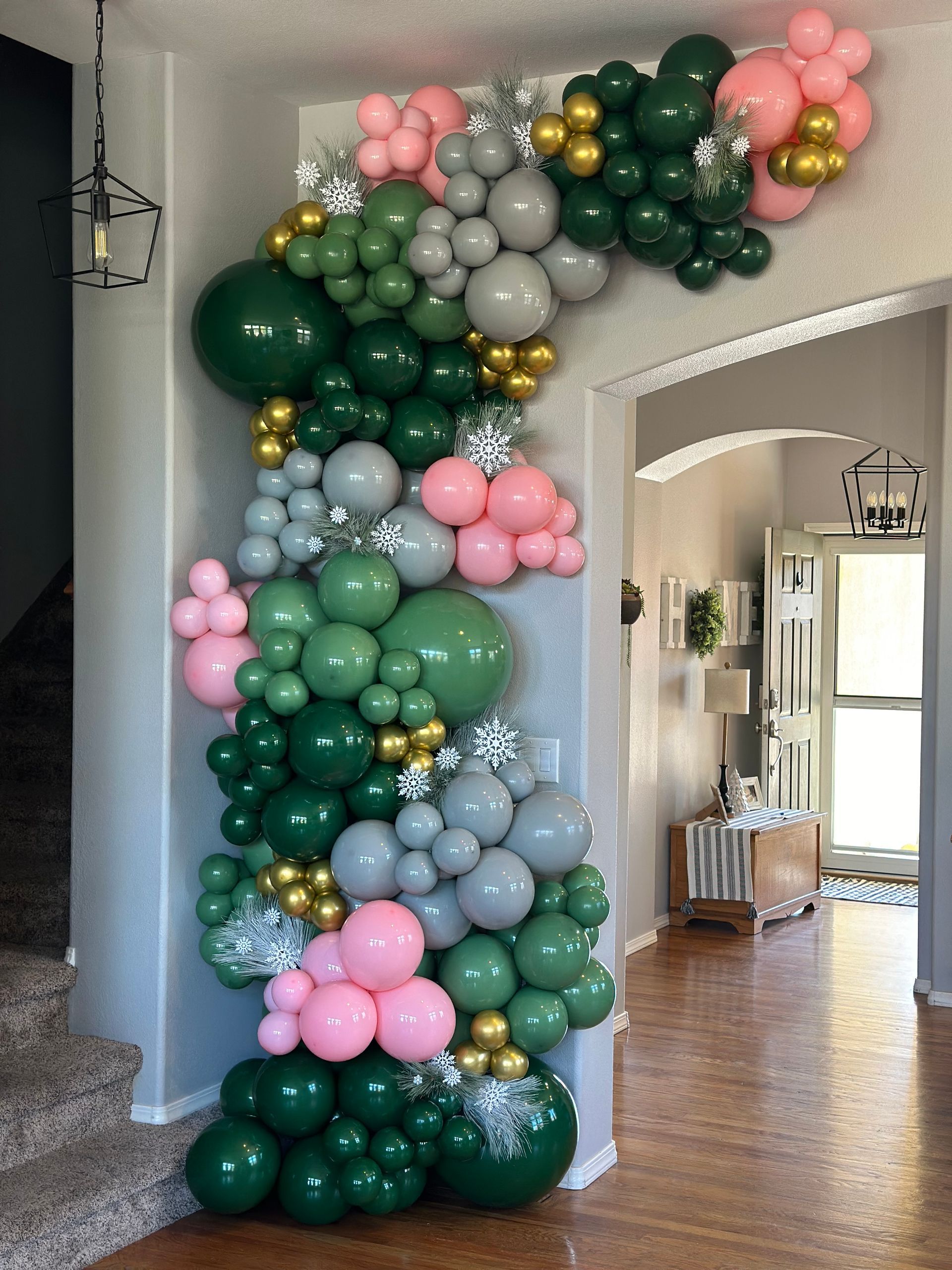 Green, pink, silver, and gold balloon archway decorating a doorway.