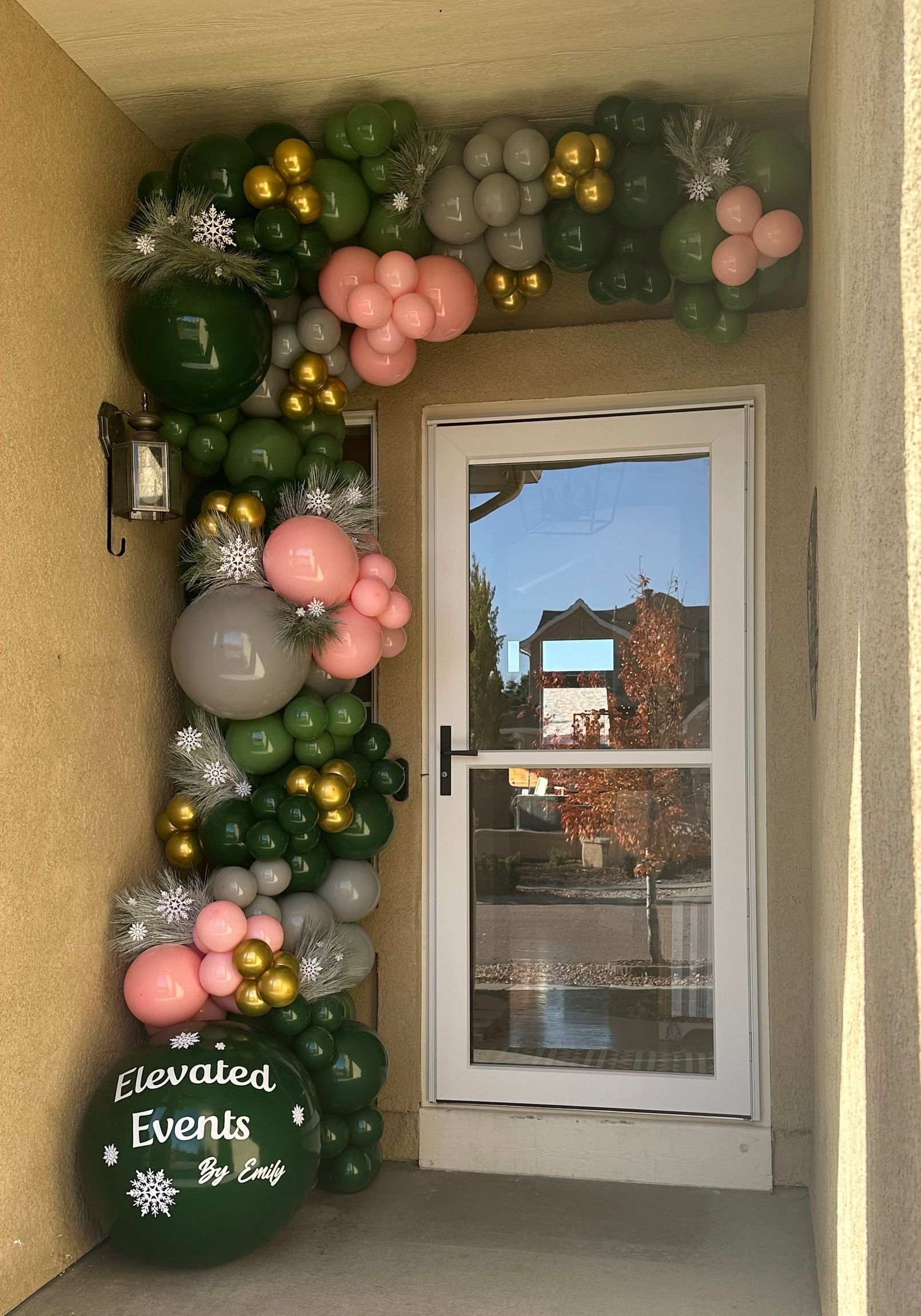 Doorway decorated with balloons in green, pink, gold, and silver. A sign says 