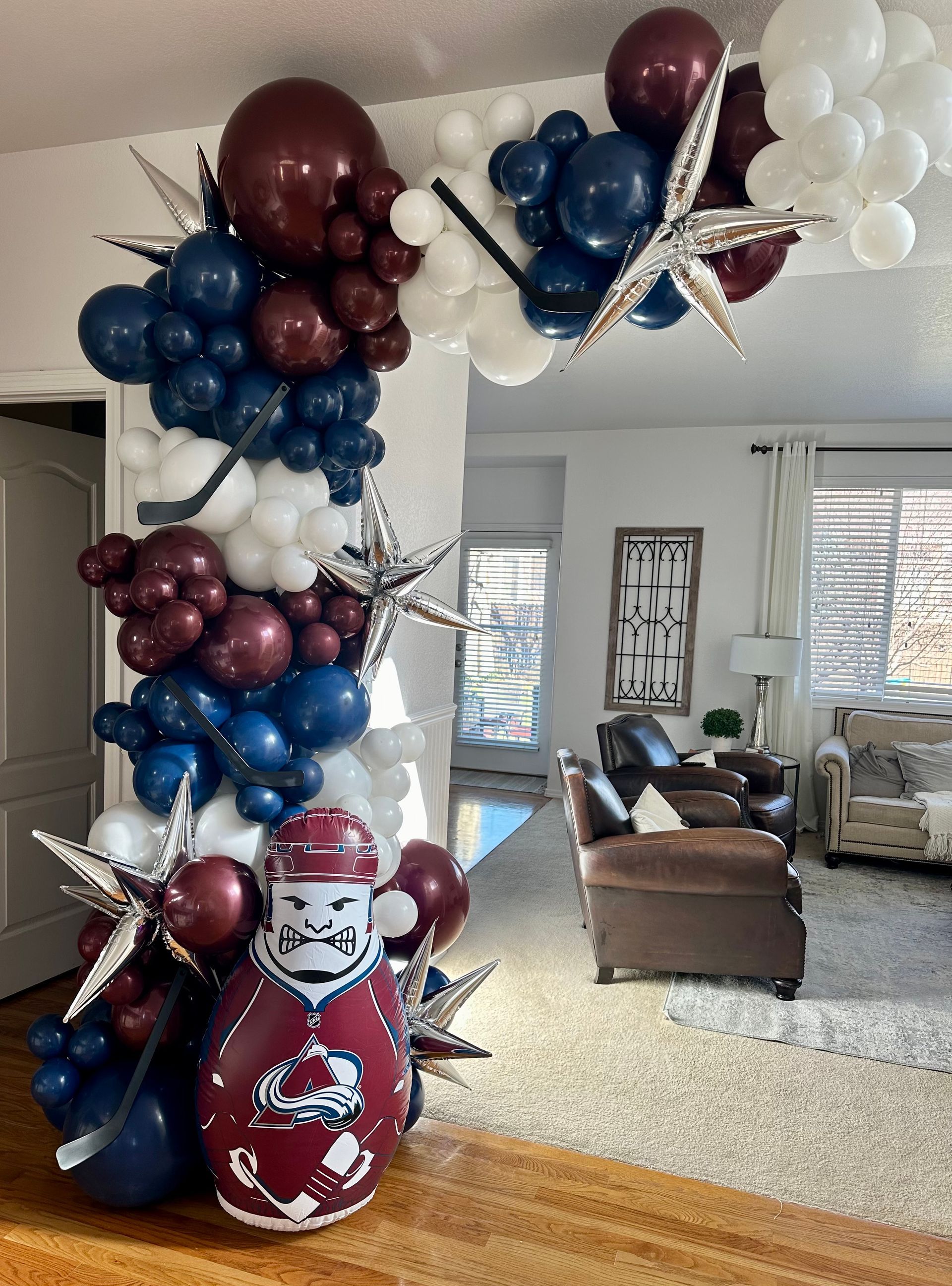Balloon arch in navy, burgundy, and white with silver star accents, near a door.