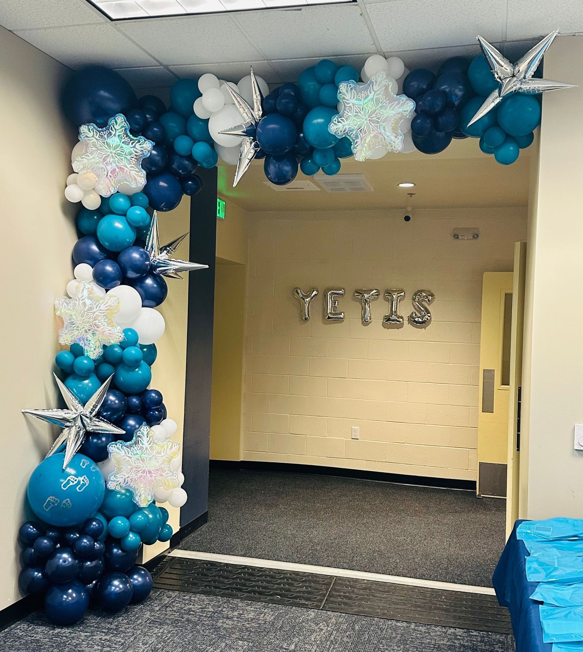 Balloon arch in shades of blue and white decorates doorway with 