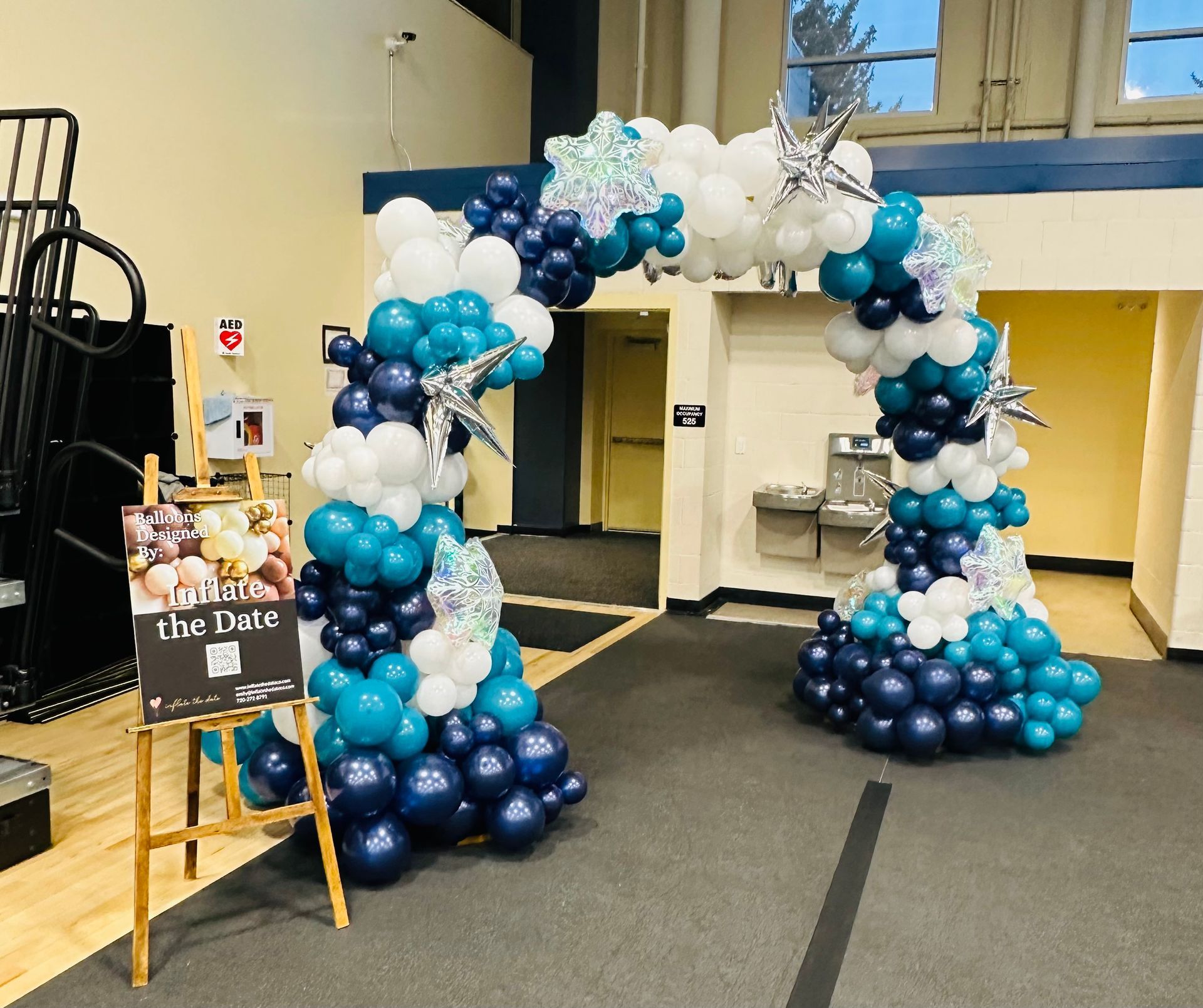 Balloon arch in shades of blue and white, with star accents, framing a doorway.