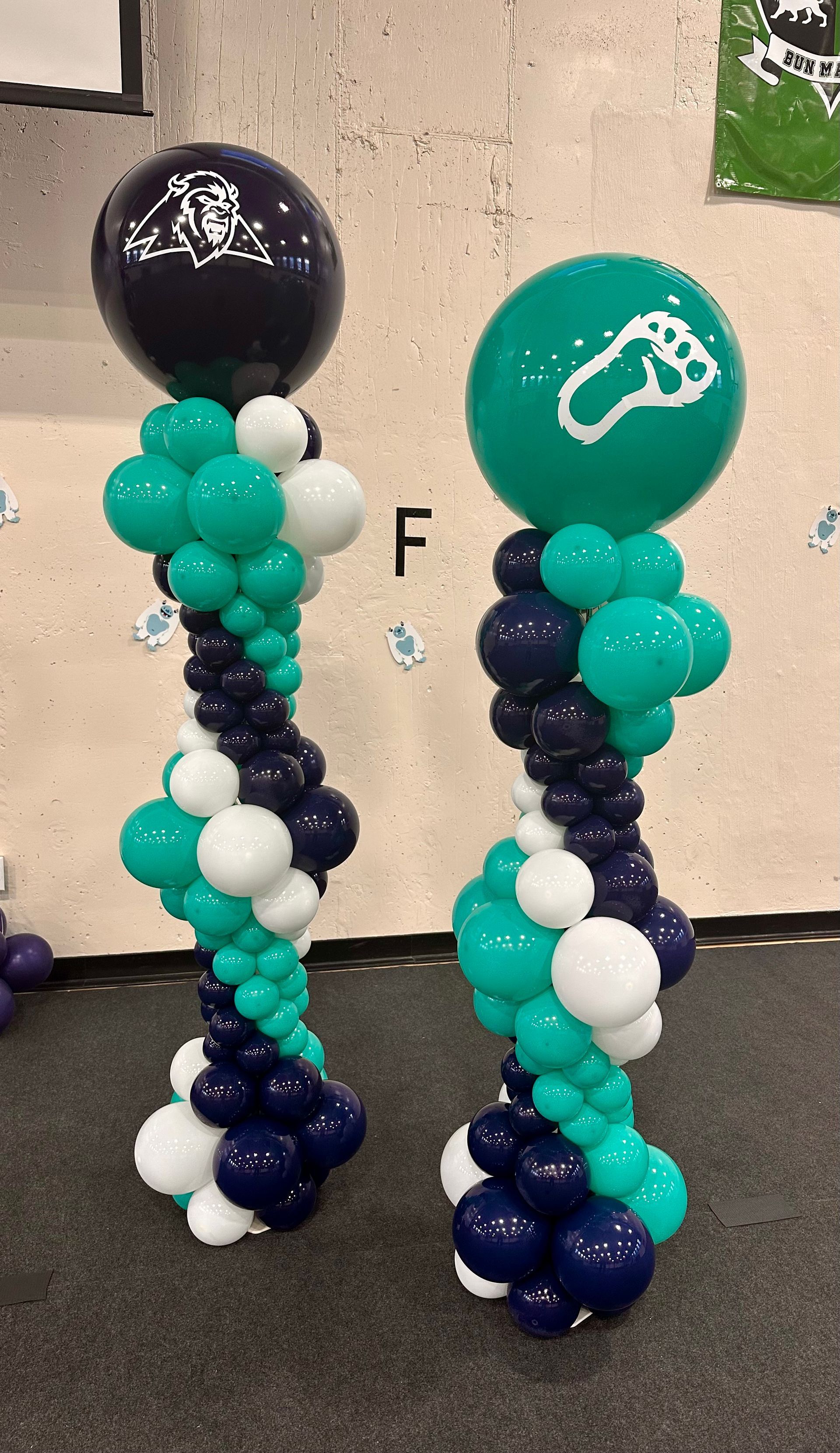 Two balloon columns: one navy/white/teal with a navy top, one teal/navy/white with a teal top.