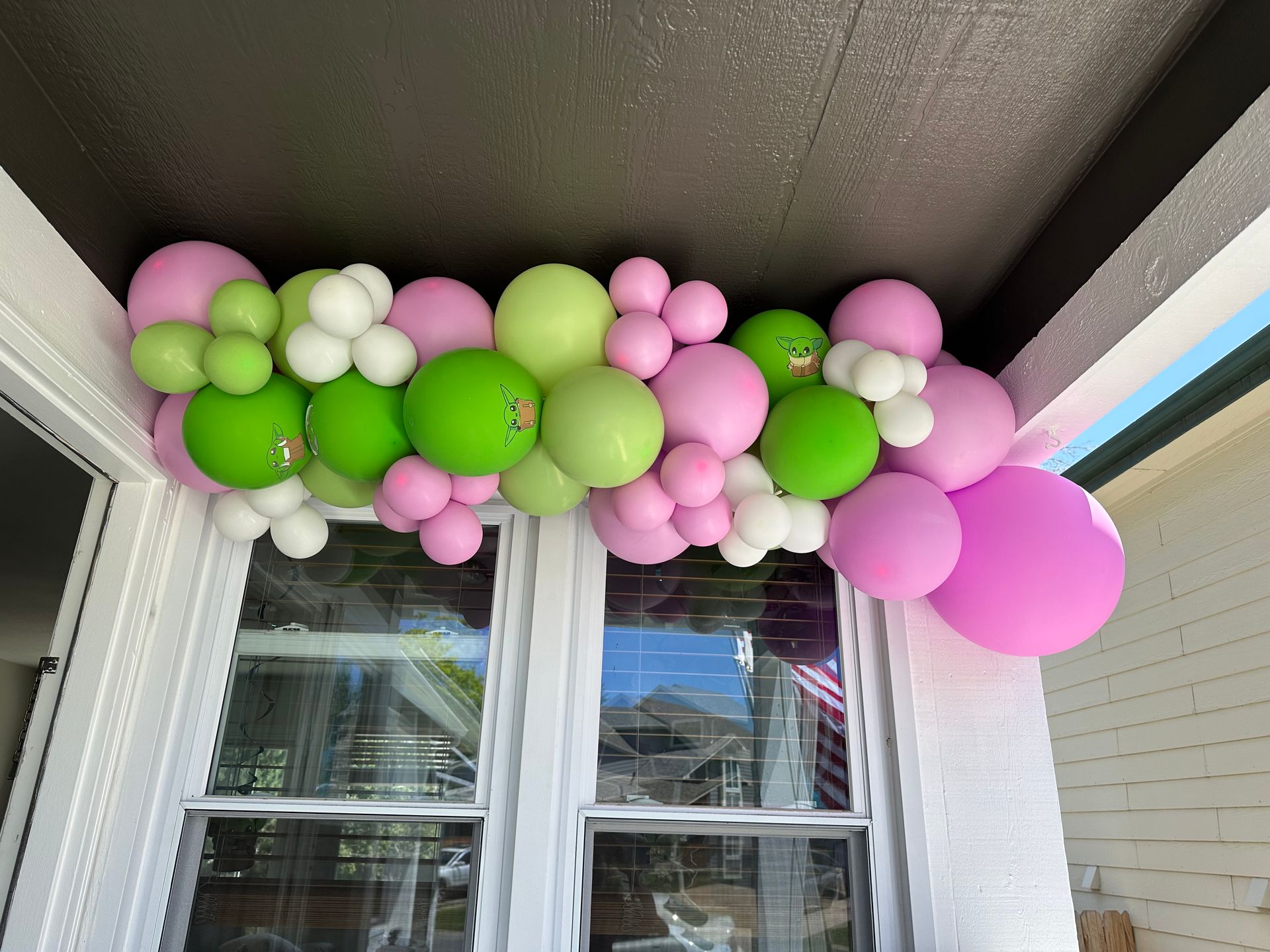 Balloon garland in pink, green, and white, draped over a window.