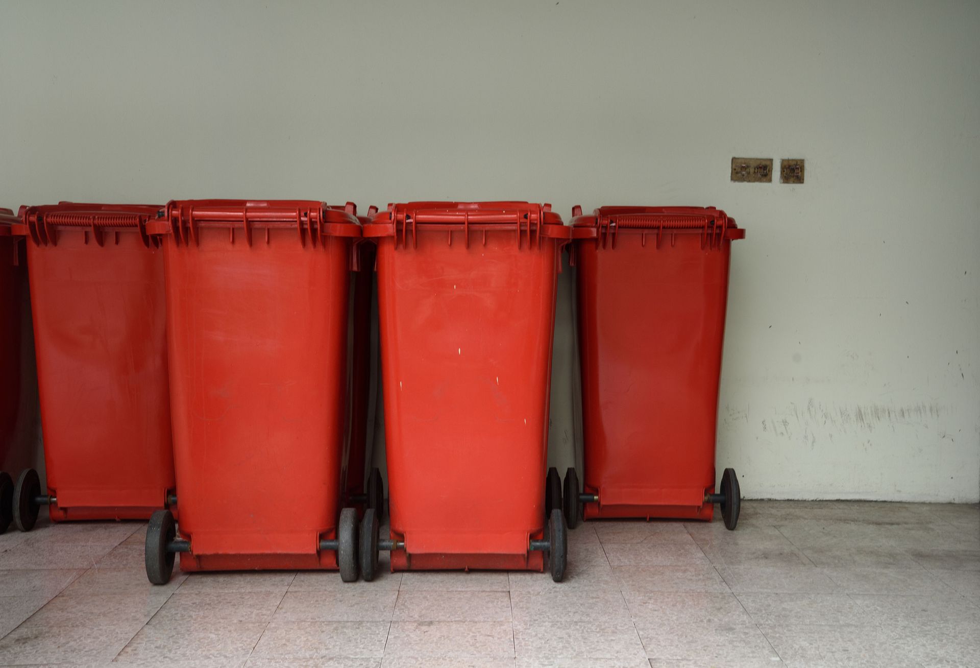 A row of red trash cans are lined up in a garage