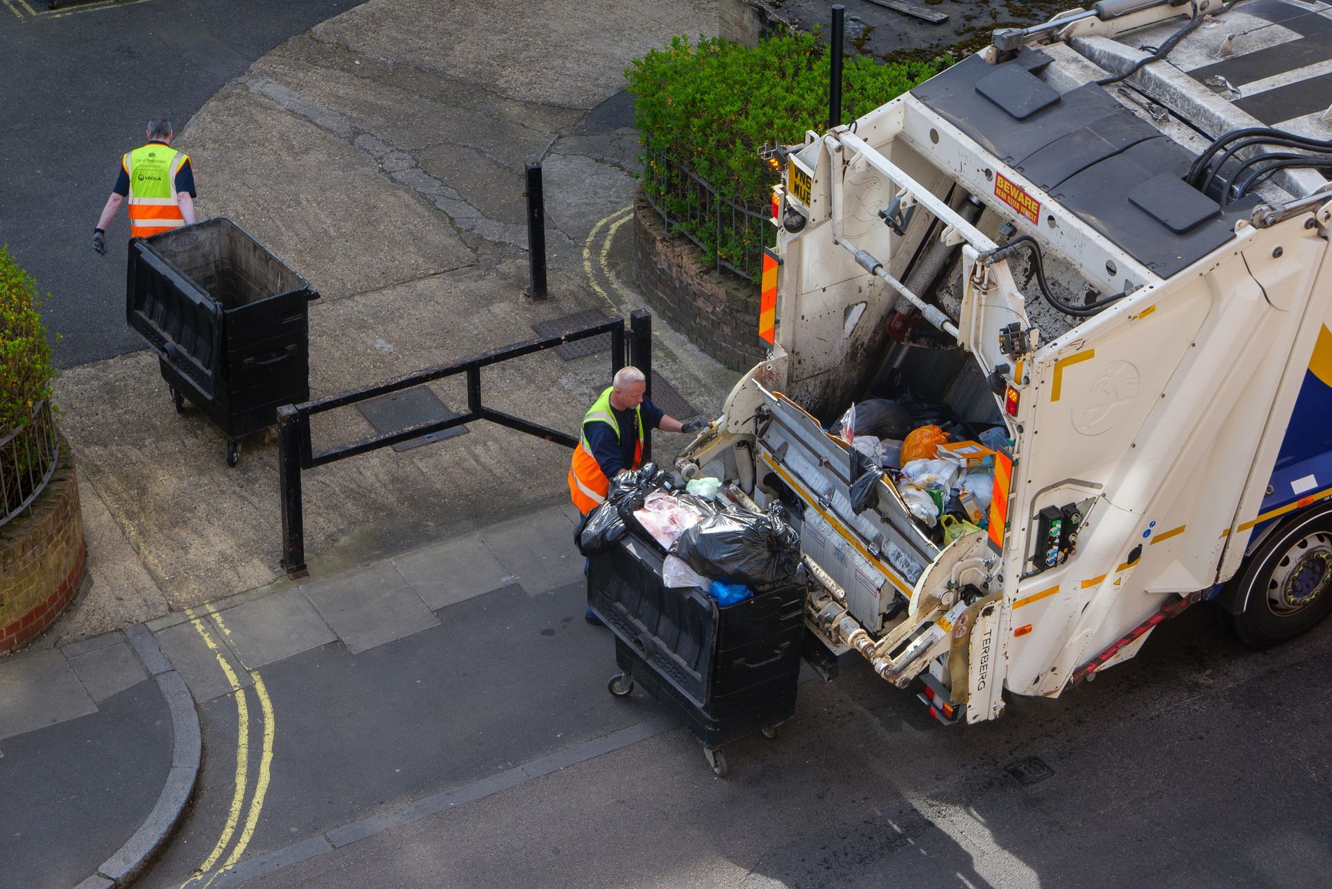 A garbage truck is picking up trash on the side of the road