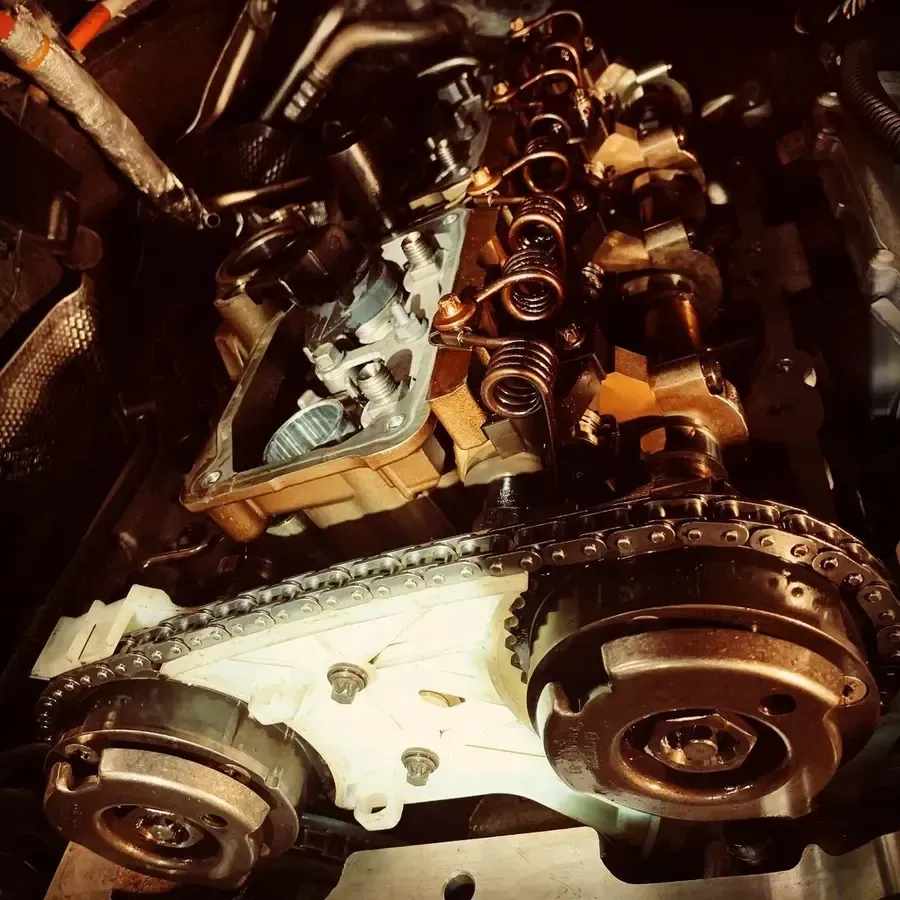 Engine parts, including timing chain and camshafts, are being worked on in an engine bay.