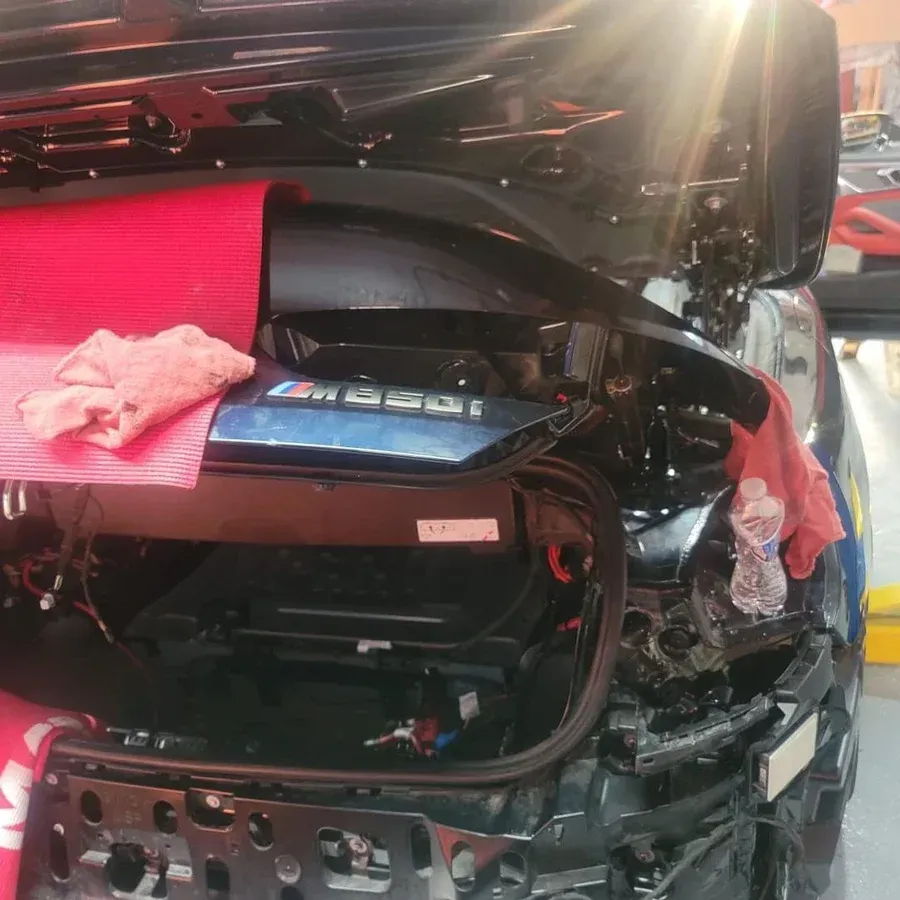 Black car trunk open, revealing components, red cloth, and water bottle.