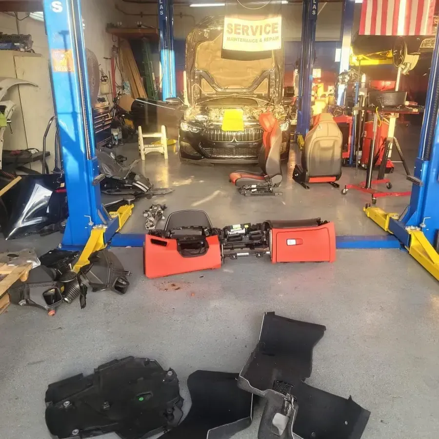 A car repair shop with a car on a lift and parts scattered around.