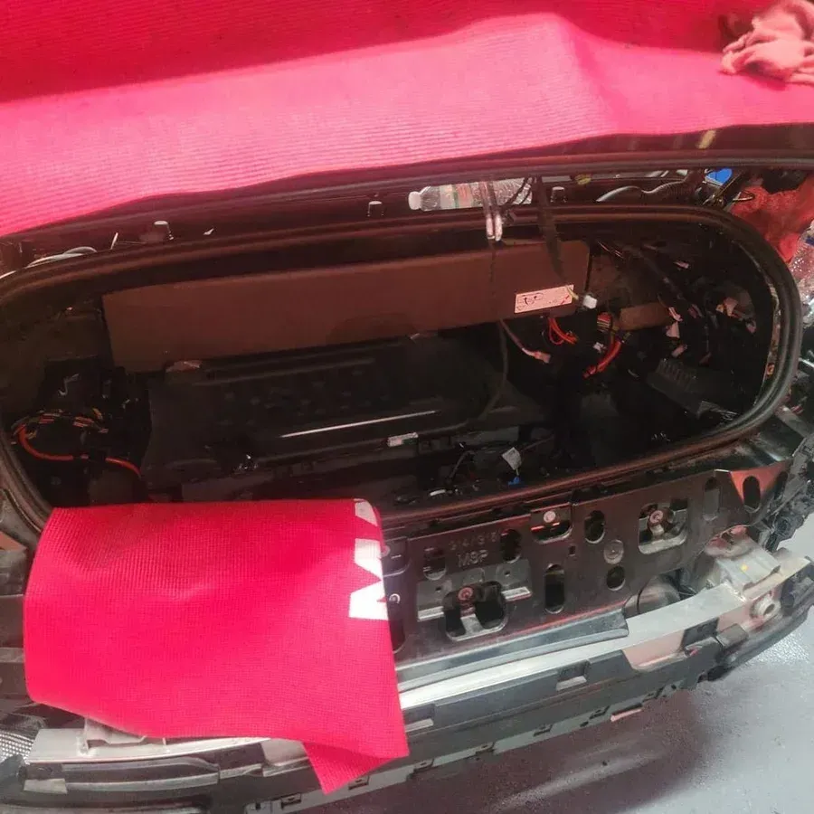 Open car trunk with red protective cover and exposed internal components.