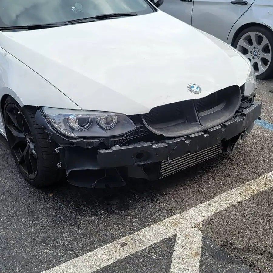 White BMW with front bumper damage, parked outside.